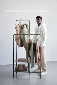 a man standing next to a rack of clothes with the words unique style support you can count on